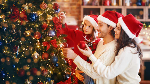photo d'une famille heureuse qui décore un sapin de Noël